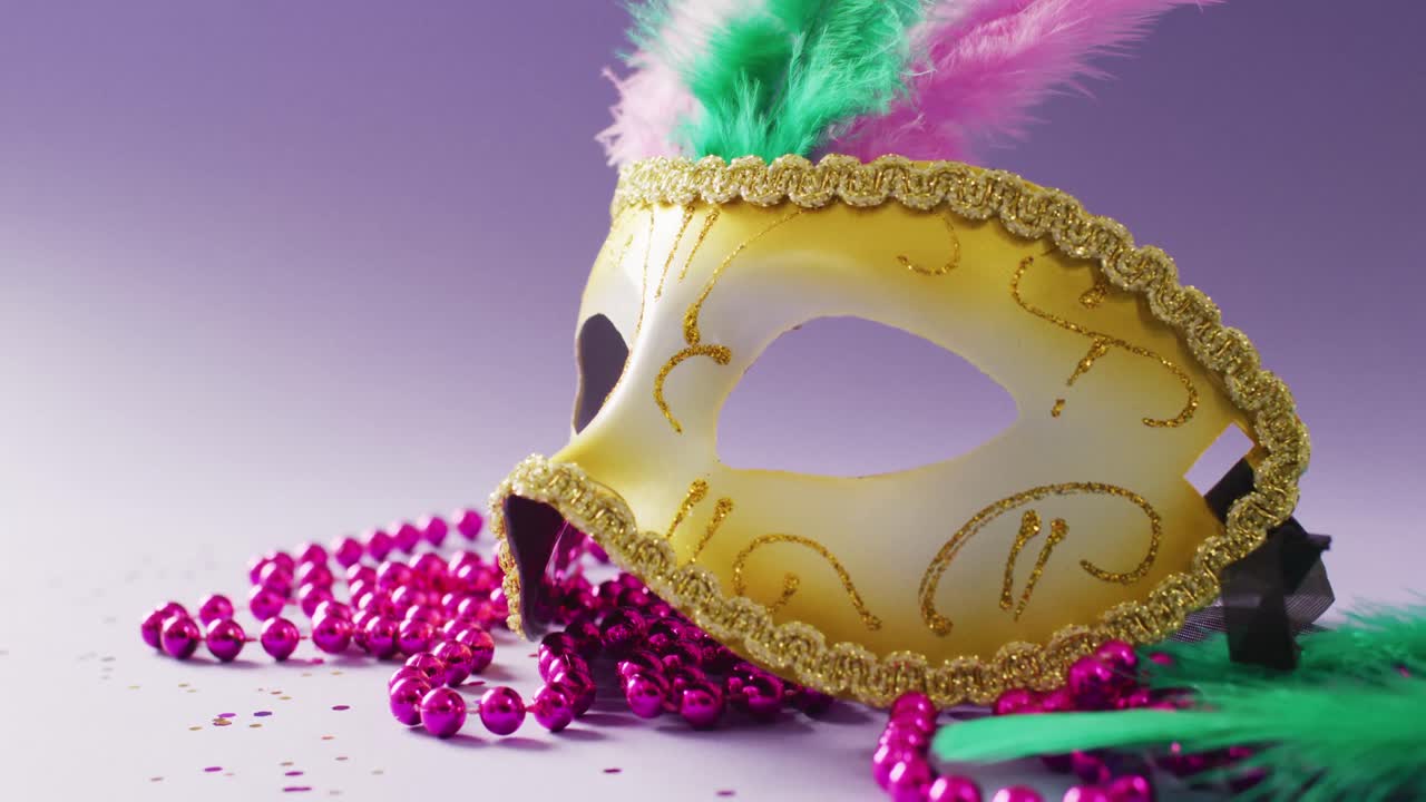 보라색 배경에  ⁇ 털과 분홍색 마디 그라 구슬이 있는 카니발 마스케레이드 마스크의 비디오
