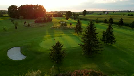 Hermosa-Vista-Aérea-Campo-De-Golf-Verde-Y-Agujero-Al-Atardecer-En-La-Naturaleza