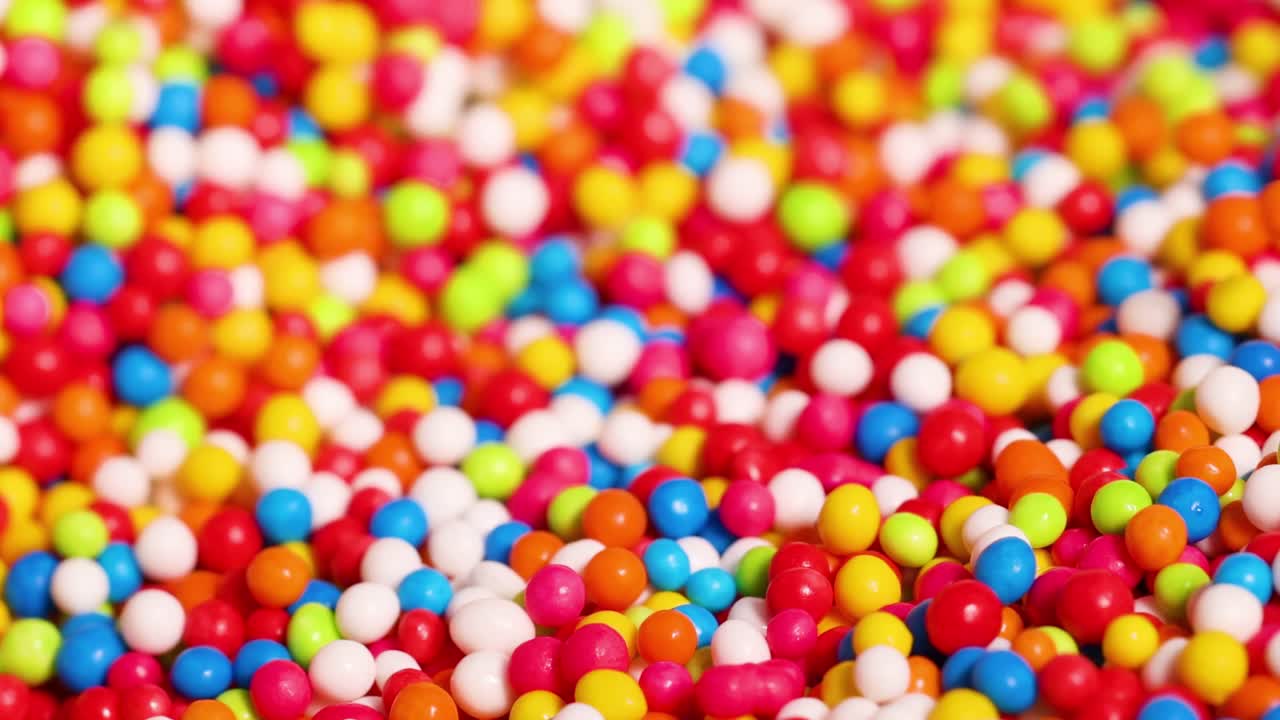 Fingers interacting with a vibrant mix of small, colorful sprinkles in a detailed close-up view.