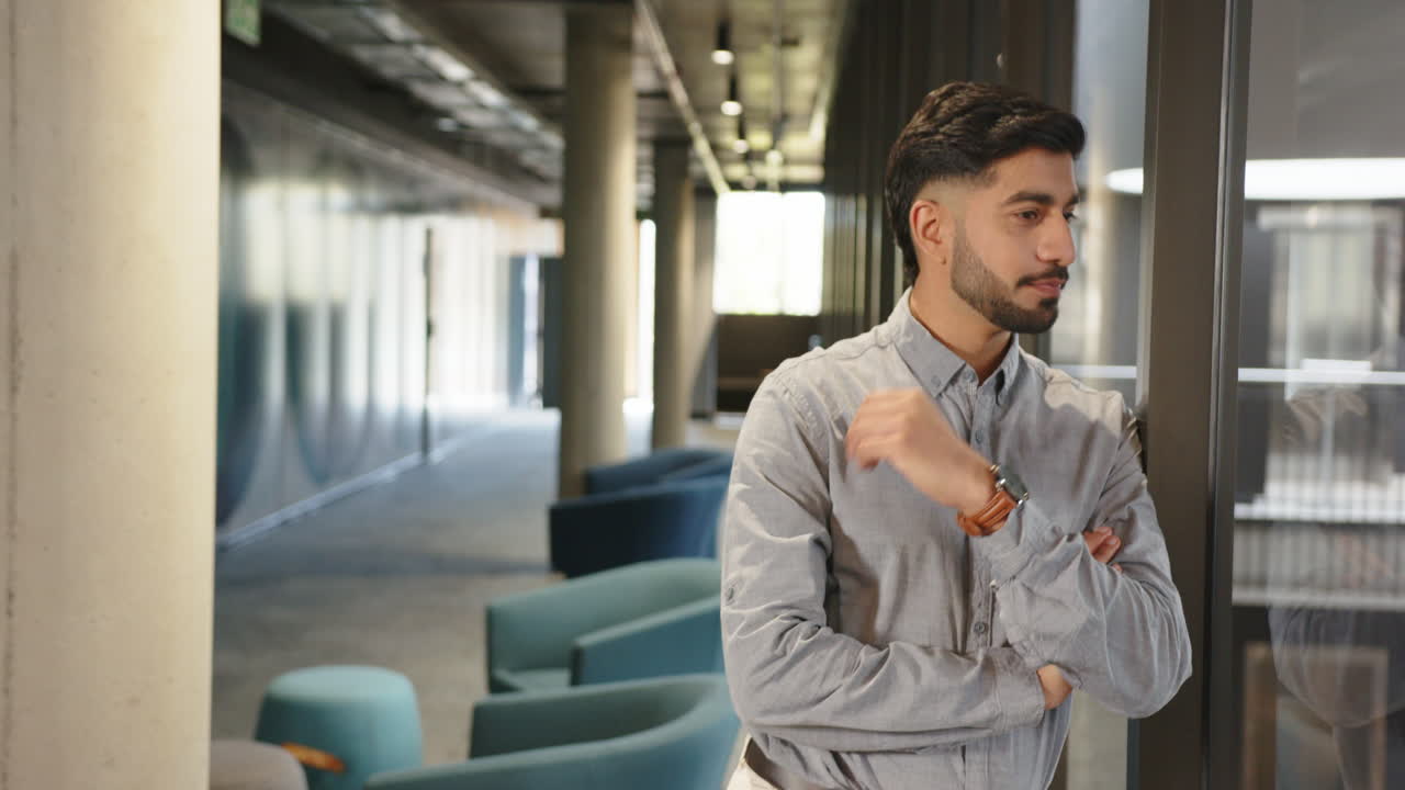 Business professional standing in modern office hallway, looking out window