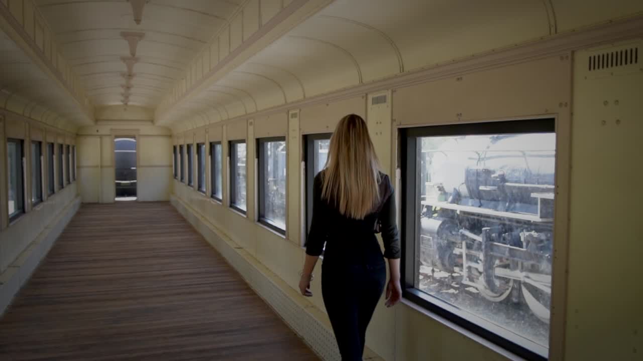 una joven misteriosa caminando en un vagón de tren abandonado.