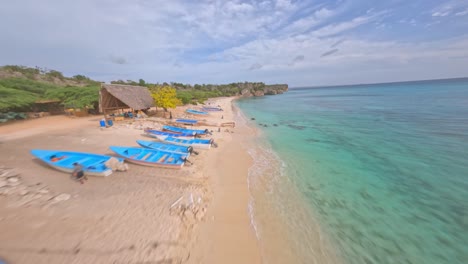 Dynamic-aerial-flight-over-tropical-beach,-beautiful-clear-water-and-restaurant-in-Pedernales,Dominican-Republic