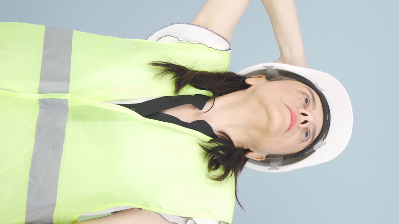 vertical video of looking up, the engineer is holding her hard hat. 엔지니어가 그녀의 하드 헤트를 들고 있습니다.