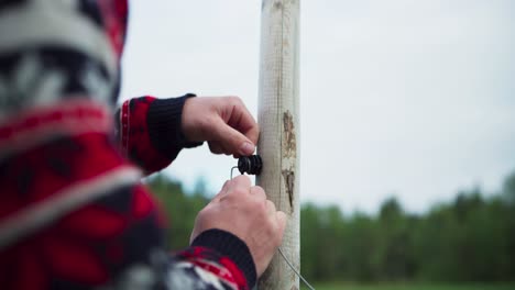 person removes wire from fence post. closeup