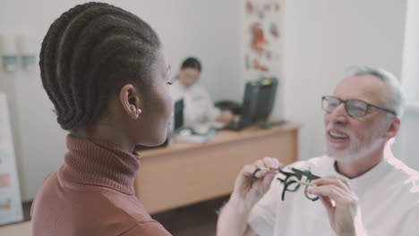 an ophthalmologist fits special optometry glasses on a young girl patient in his clinic for a vision test