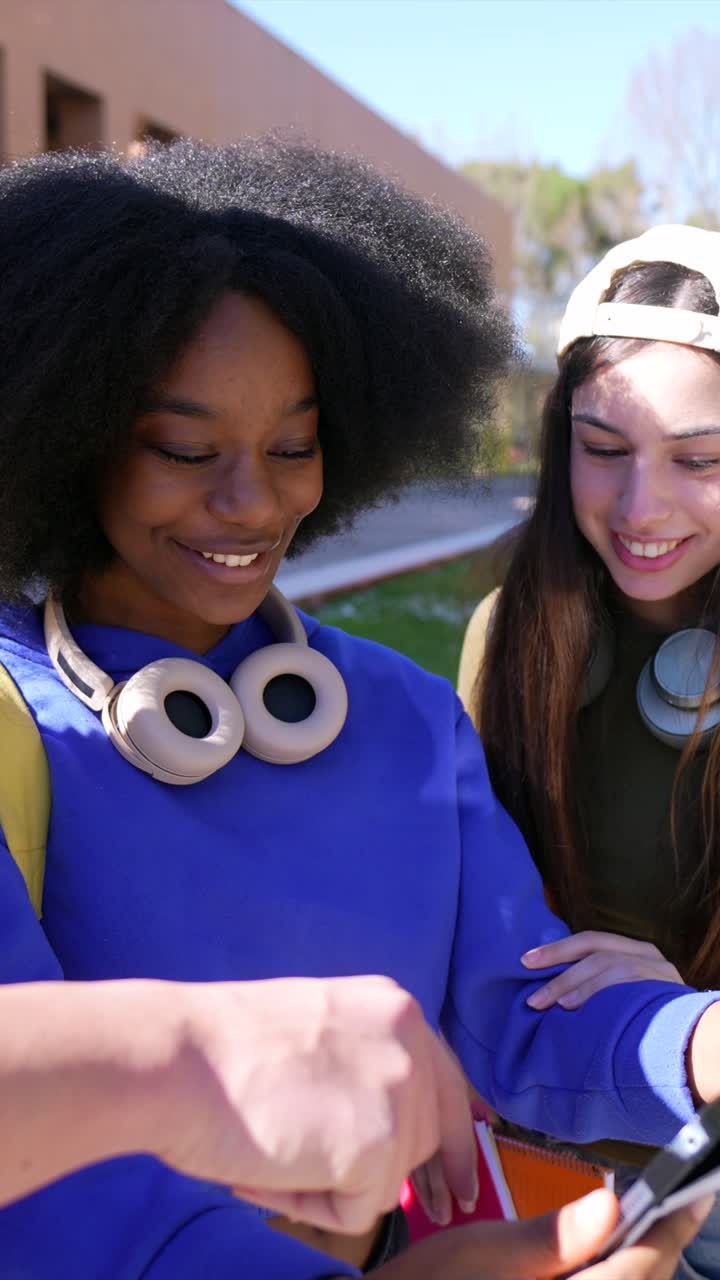 Studenti universitari di diverse etnie sorridenti e che indicano un tablet nel campus