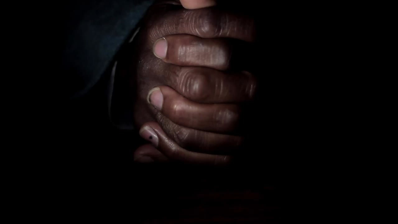 man praying to god with hands together Caribbean man praying with black background stock footage