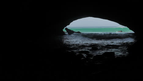 Olas-Rodando-En-Una-Gran-Cueva-Oscura,-Exterior-Soleado,-Waenhuiskrans,-Sudáfrica