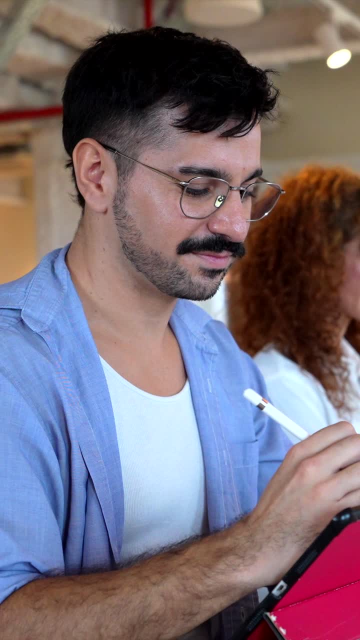 Uomo concentrato che usa un tablet digitale con stilo in un ufficio moderno