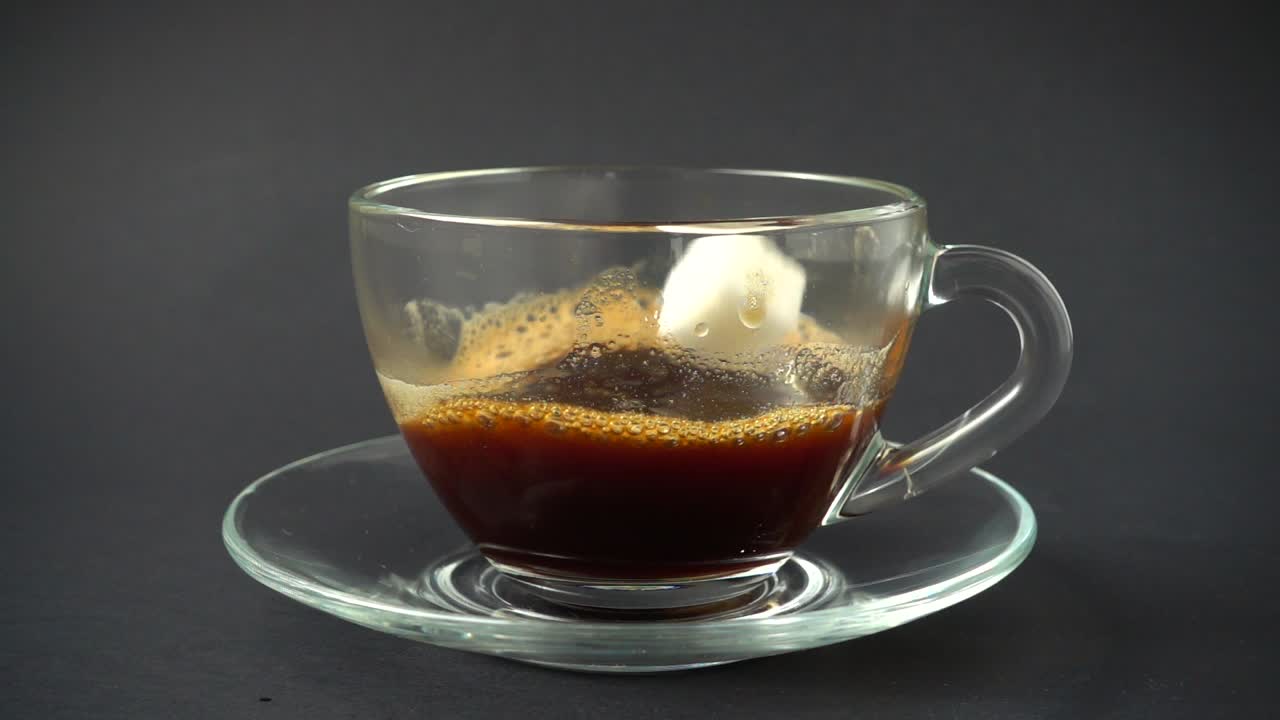 Zucchero che cade in una tazza di caffè. Movimento al rallentatore