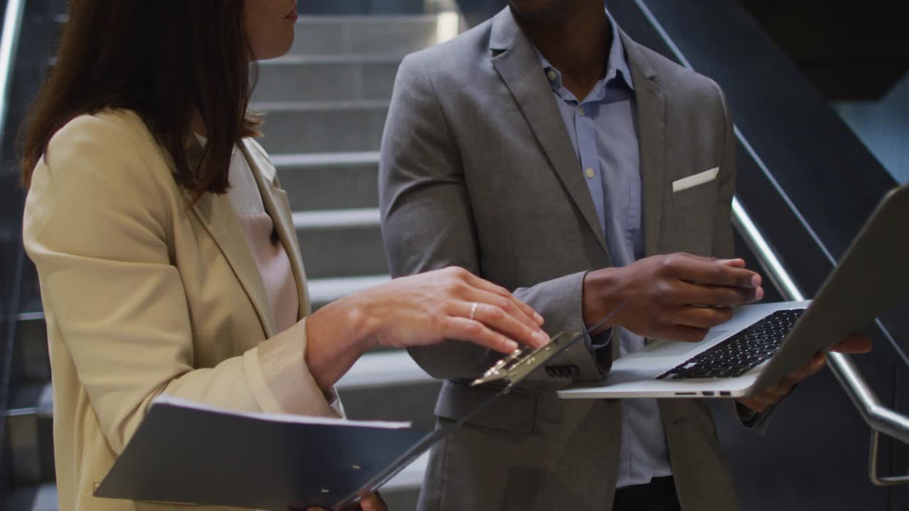 Woman tapping keypad while man typing laptop, activating waveform and numbers for business review