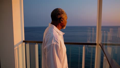 older man contemplating the sunset from a balcony