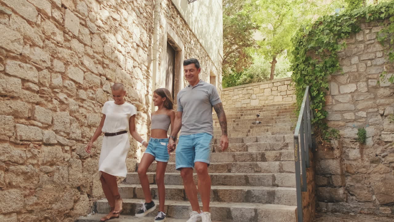 En lykkelig familie spaserer ned steintrapper i en gammel by