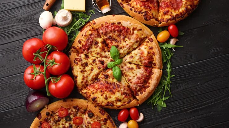 Tre pizze diverse appena servite, disposte tra ingredienti gustosi. Vista dall'alto