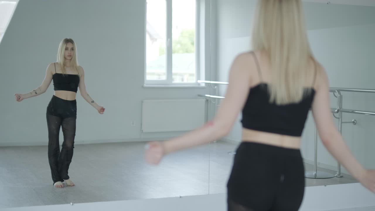 흑색 옷을 입은 소녀가 동시대를 선보이며, 여성 댄서가 하 방에서 흐르는 움직임, 몸과 손의 파동을 보여줍니다. 현대 발레 댄스 안무. 젊은 여성이 부드럽게 움직이고 있습니다.