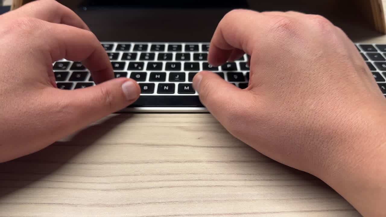 Closeup of hands typing on a keyboard at a desk, shallow depth of field office scene
