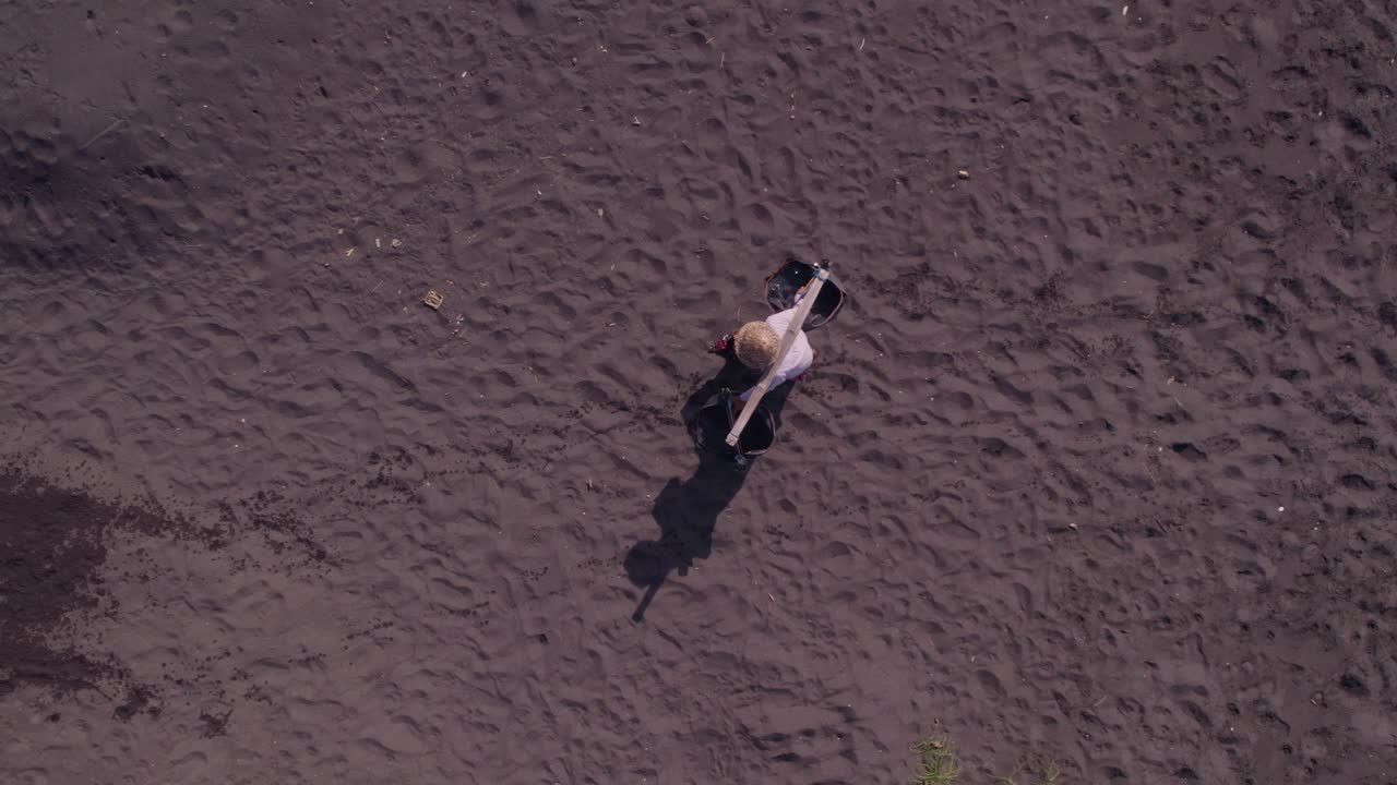 Salinai al lavoro sulla spiaggia di sabbia nera a Bali, Indonesia