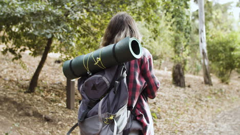 young female backpacker with camera taking pictures of forest