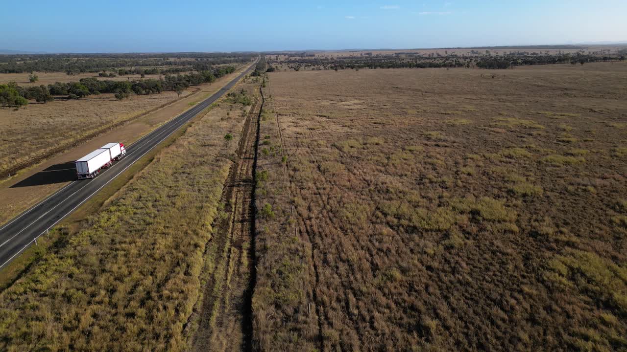 Aerial views over a large truck on a road through farmland in inland Central Queensland, Australia.