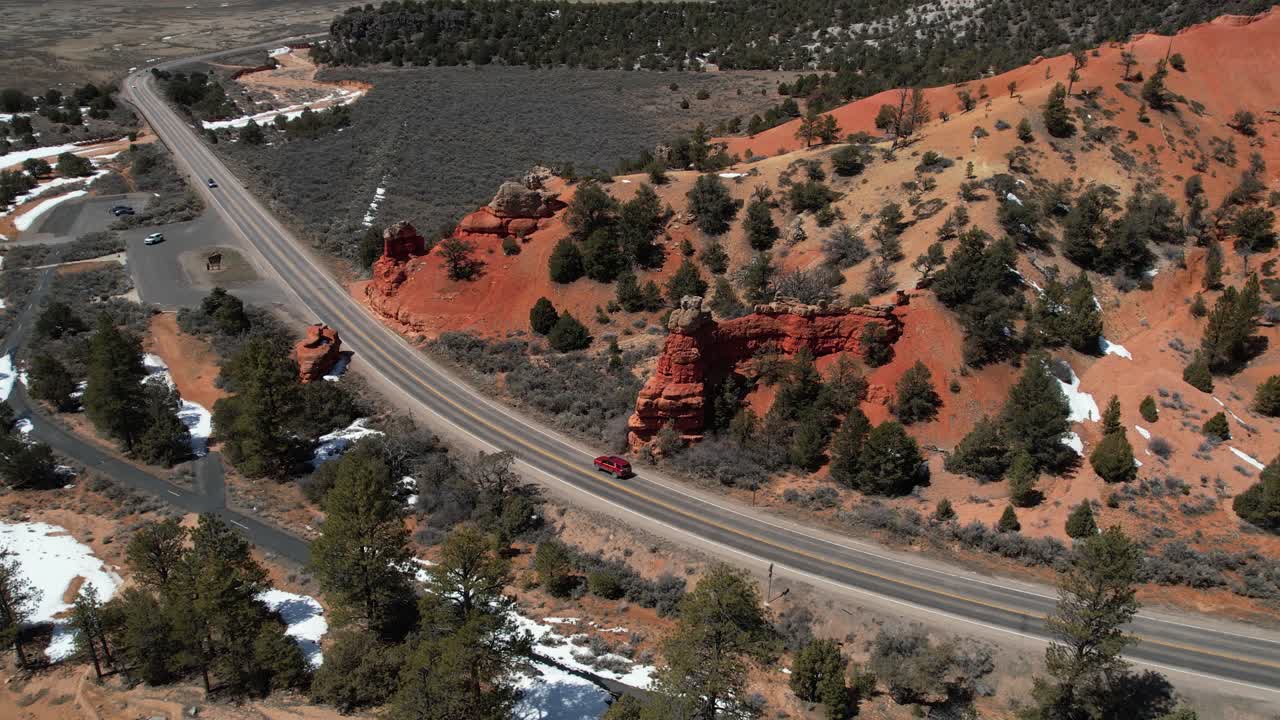 vista aérea de un vehículo suv rojo moviéndose en una ruta pintoresca en el campo de arizona, estados unidos, en un soleado día de invierno.