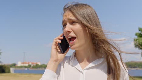 mujer hablando en su teléfono inteligente en su oreja al aire libre bajo el sol, primer plano estático