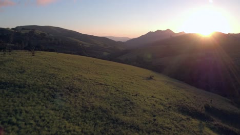 an aerial 4k drone flight with wide lens, during sunset, over the lush green hills and valleys