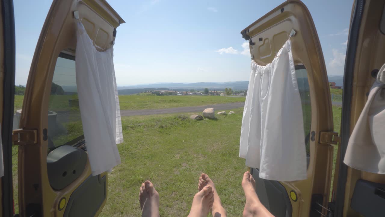 안에 젊은 부부와 함께 주차된 캠퍼 밴의 내부에서 녹색 풍경 밖으로 돌리