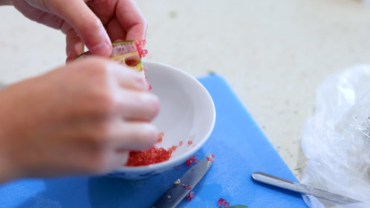 Hands extracting finger lime pulp into a bowl on a kitchen counter