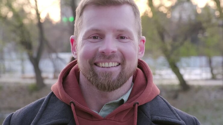 video ravvicinato di un uomo sorridente che indossa un cappuccio rosso in una città americana a metà giornata in un freddo giorno invernale