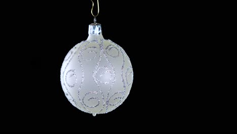 adorno de bola de navidad blanco único con rayas de brillo plateado y fondo negro, primer plano