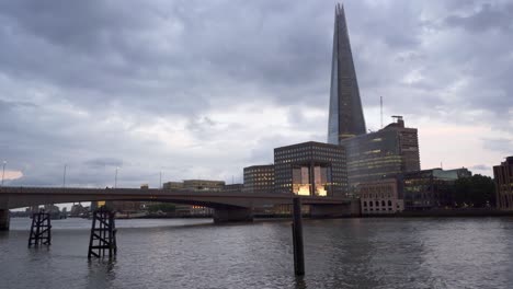 busy view of london bridge with the cityscape of the southbank and the shard skyscraper in the background at dusk