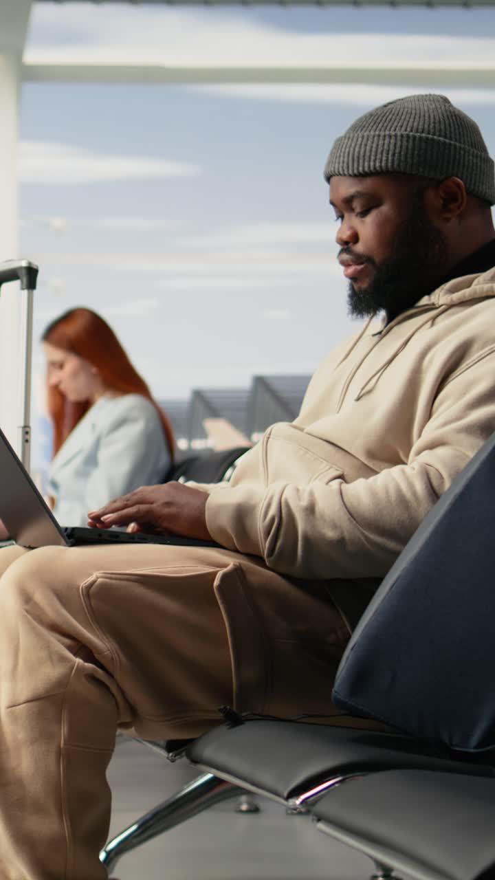 Vertical Video Independent Professional Man Typing On Laptop In Airport Waiting Area