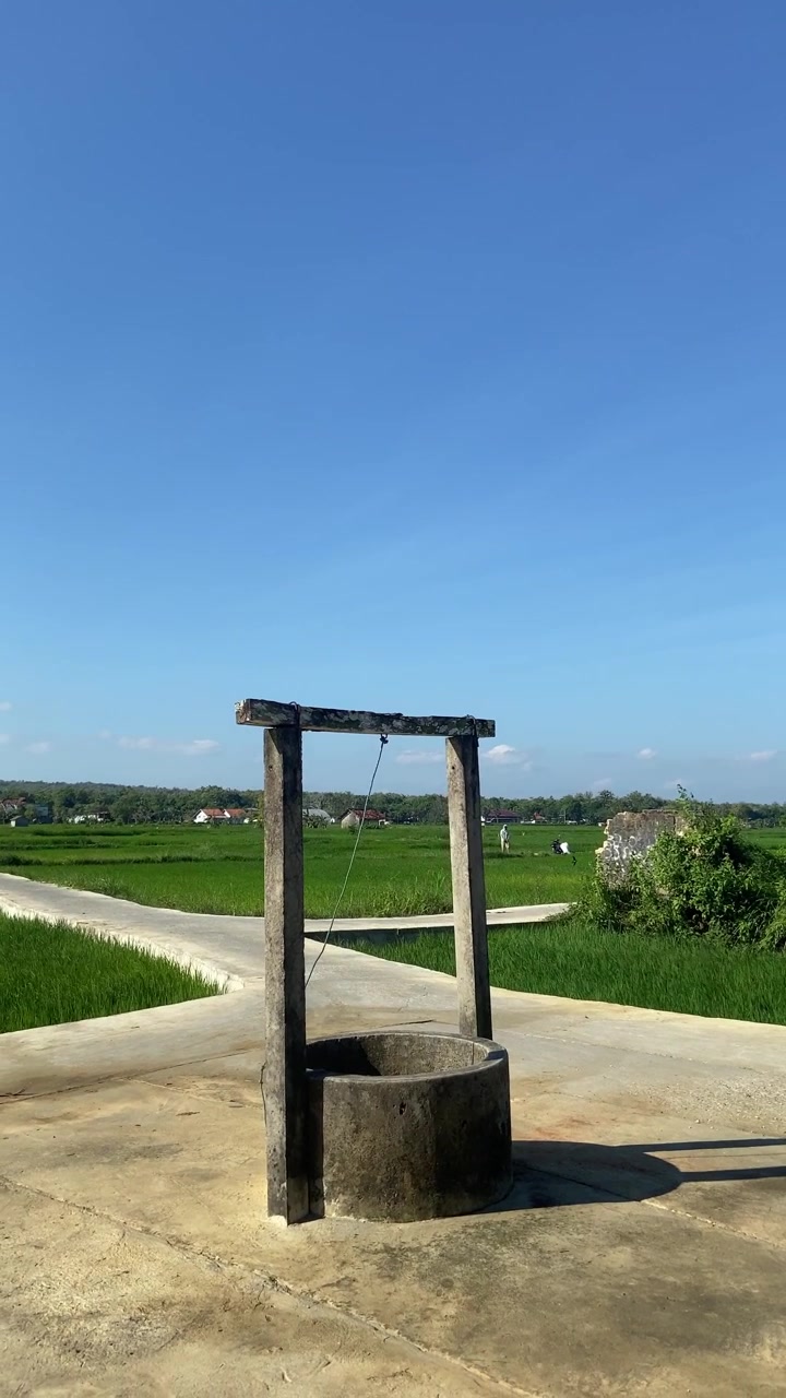 澄み切った青空の下、田園の田んぼの風景にある伝統的な井戸
