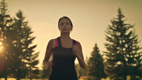 young woman runner running in park at sunset. fitness woman jogging in park