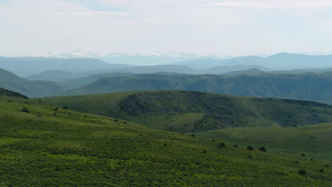 aerial drone showing layers and layers of colorado rocky mountains with forest trees and snow-capped peaks