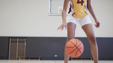 portrait of african american female basketball player training in indoor court, in slow motion