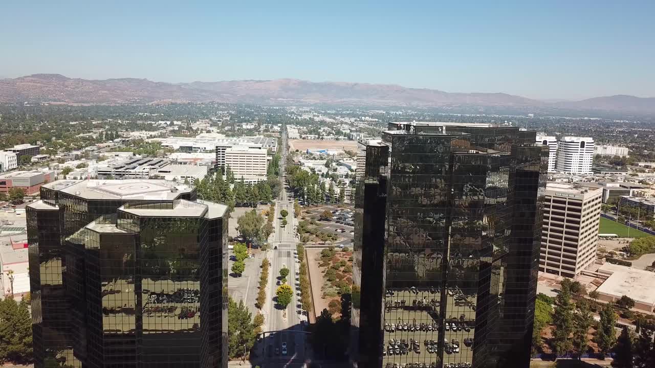Drone flight between modern mirrored buildings of AIG Capital Service in Woodland Hills. Main street in district of LA, California. Aerial wide shot.