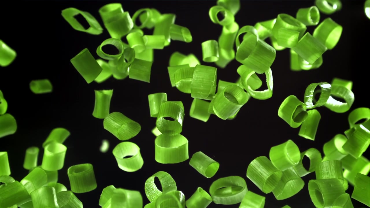 Chopped Green Onions Falling in Slow Motion on Black Background