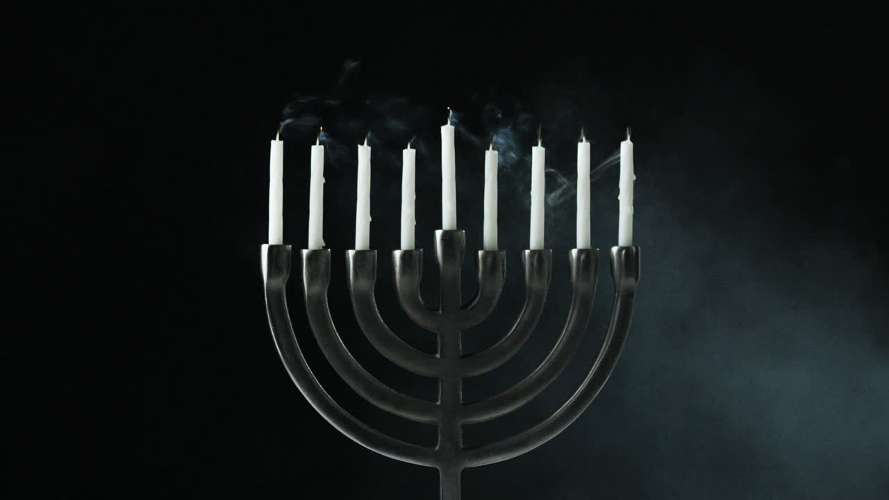 una fila de nueve velas blancas ardiendo en una menorá se apagan, vista delantera