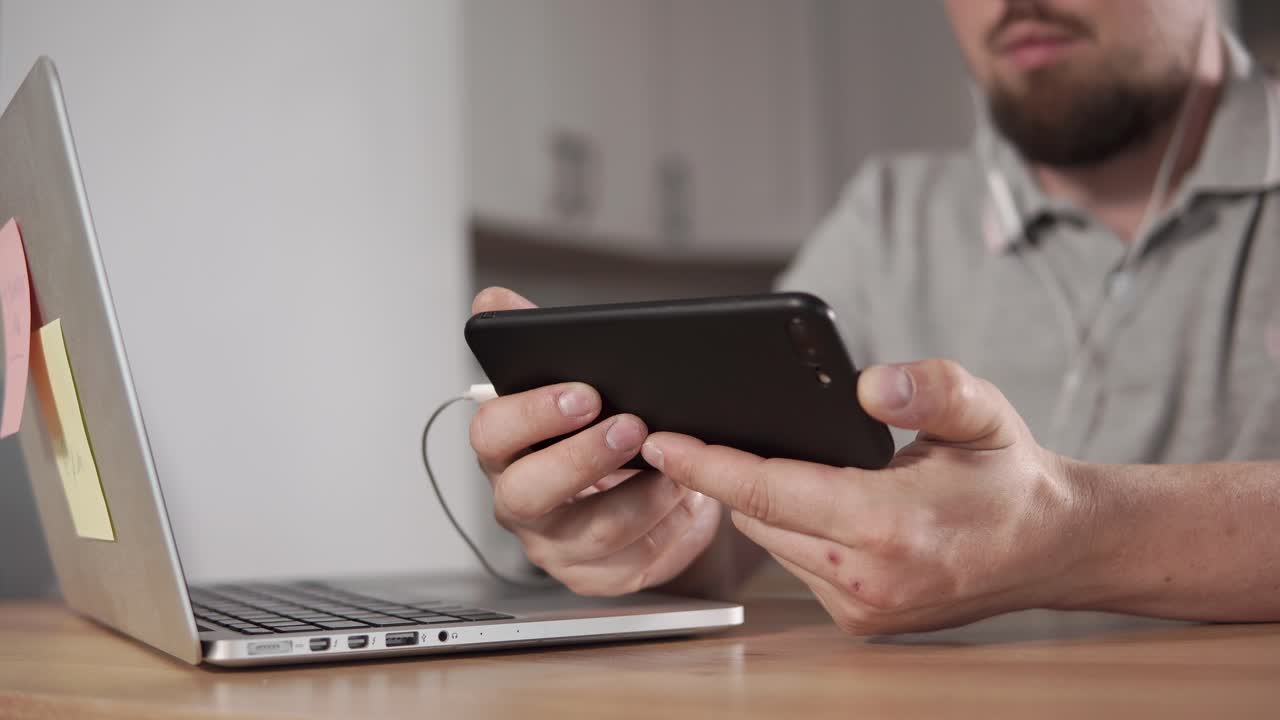 hombre usando teléfono inteligente y computadora portátil en casa