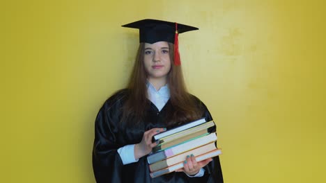 caucasian girl student holds many books while staying in front of camera with graduating diploma in her hands. master of theology