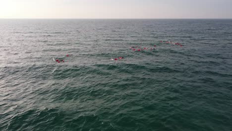 swimmers in the sea near castelldefels beach, barcelona, with safety buoys, aerial view