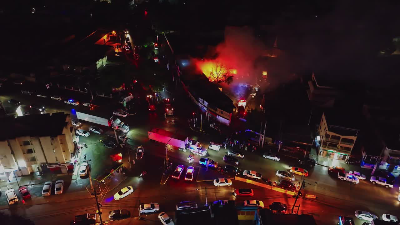 Aerial view of trucks and traffic passing a building fire and emergency vehicles