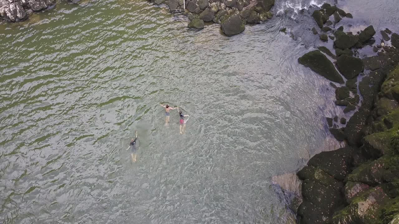 tres jóvenes nadando en el río doubs, grandes rocas y musgo, neuchatel, suiza