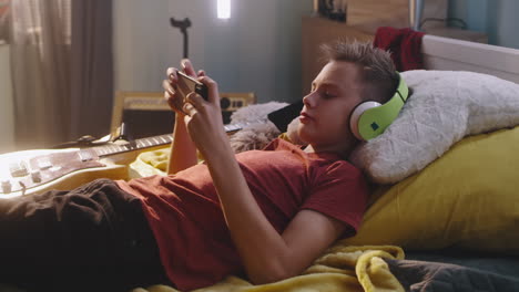 teenage boy relaxing in his bedroom playing games