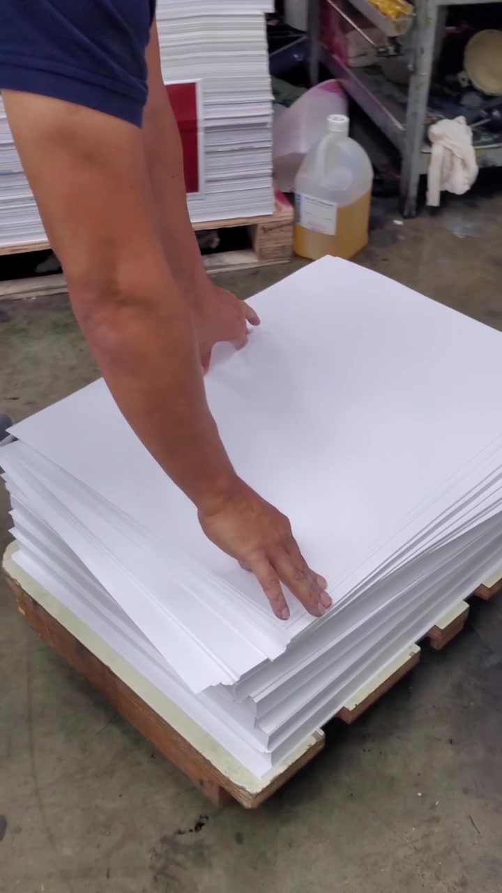 Vertical video Close up shot operator organizing large reams of blank paper stock for production in a printing factory