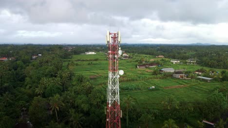 primer plano de una torre de telecomunicaciones con un dron en una aldea rural de indonesia