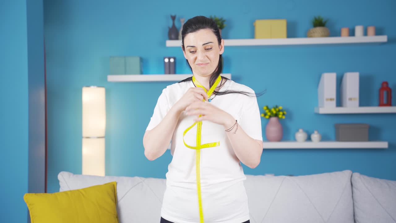 불행한 사람이 측정 테이프로 몸무게를 측정하고 있습니다.