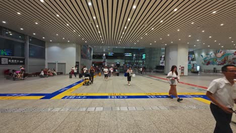 people walk through the brightly lit interior of guangzhou airport, carrying luggage.