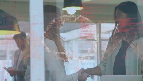 Two-female-executives-shaking-hands-with-each-other-in-an-office